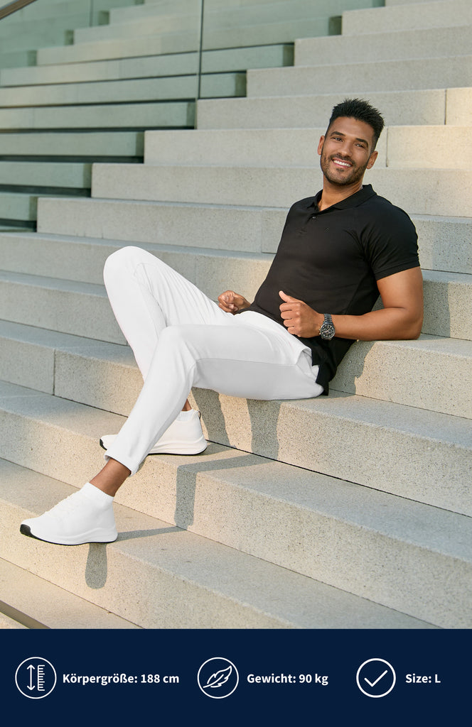 Model trägt ein schwarzes Slim Fit Poloshirt und liegt dabei angelehnt auf einer hellgrauen Treppe.