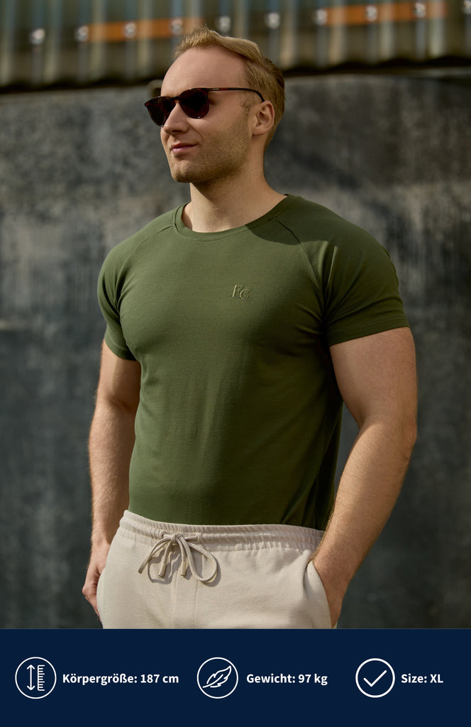 Model trägt ein olivgrünes Slim Fit T-shirt mit Stretch Raglan und eine Sonnenbrille.