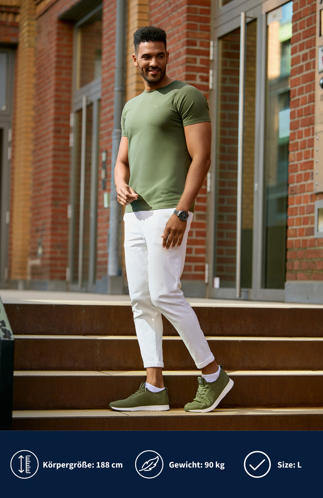 Model trägt ein olivgrünes Slim Fit T-Shirt und steht auf einer Treppe.